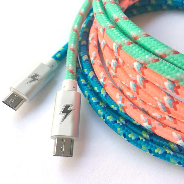 Two braided charging cables with USB-C connectors feature colorful woven designs—one cable is predominantly blue with yellow and green accents, and the other is salmon and teal. Both connectors have a lightning bolt symbol on them, indicating fast charging capability.