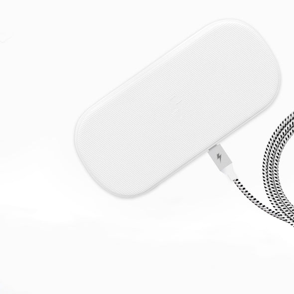A rectangular white wireless charging pad with a subtly textured surface is connected to a braided black-and-white charging cable. The pad and cable feature lightning bolt emblems, indicating their appropriate usage for fast charging devices.
