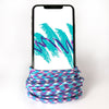 A smartphone with a black frame displaying a white screen with teal and purple abstract brush strokes stands upright, encircled by the ChargeCords Jazz Lightning Cable [5 ft / 1.5m length], an Apple MFi Certified colorful rope-like lightning cable featuring purple, blue, and white patterns. The background is white. Compatible with iPhone and iPad.