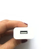 A person with red-painted nails is holding a Charge Cords USB-A 2.4a Wall Block with a visible USB port against a plain white background.